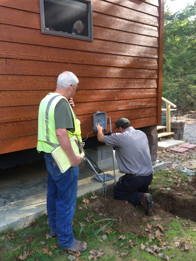 Crew brings fiber cable from underground up to side of house. Installation of service box on the house.